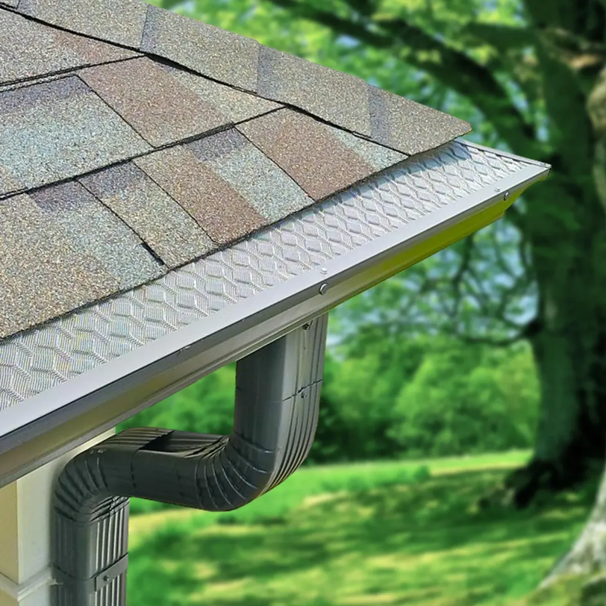 A gutter guard fitted along a shingle roof edge